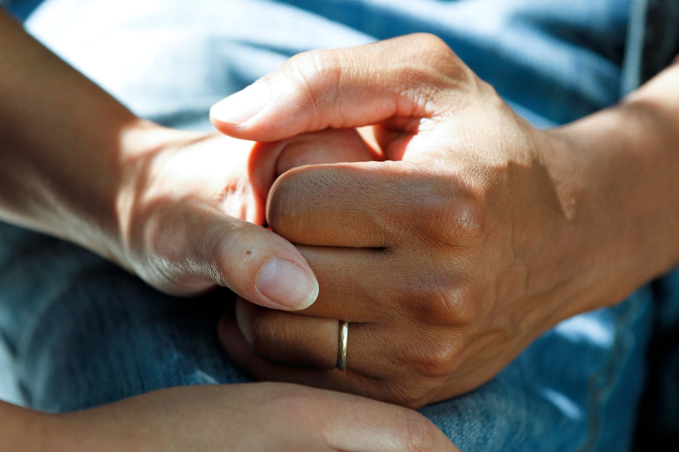 An older and a younger hand held together in warm light
