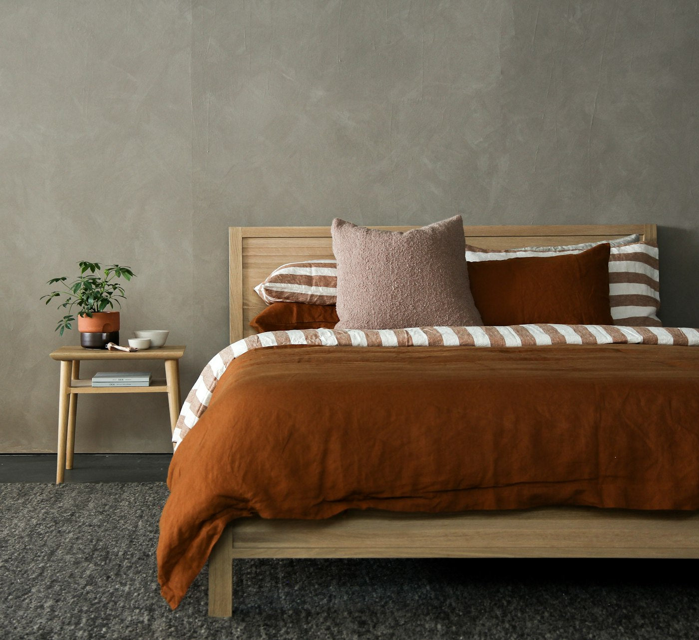 A calm, modern bedroom with a bedside table and warm natural light